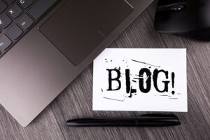 Picture of a laptop with a sign saying blog next to it