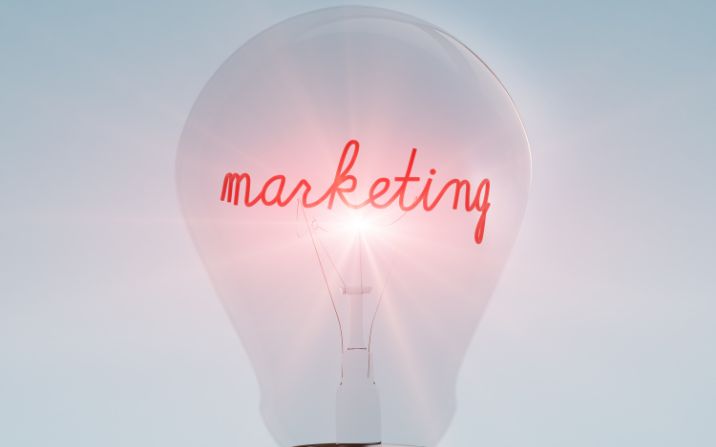 Image of a lightbulb with the word marketing written in script across the light source in red.